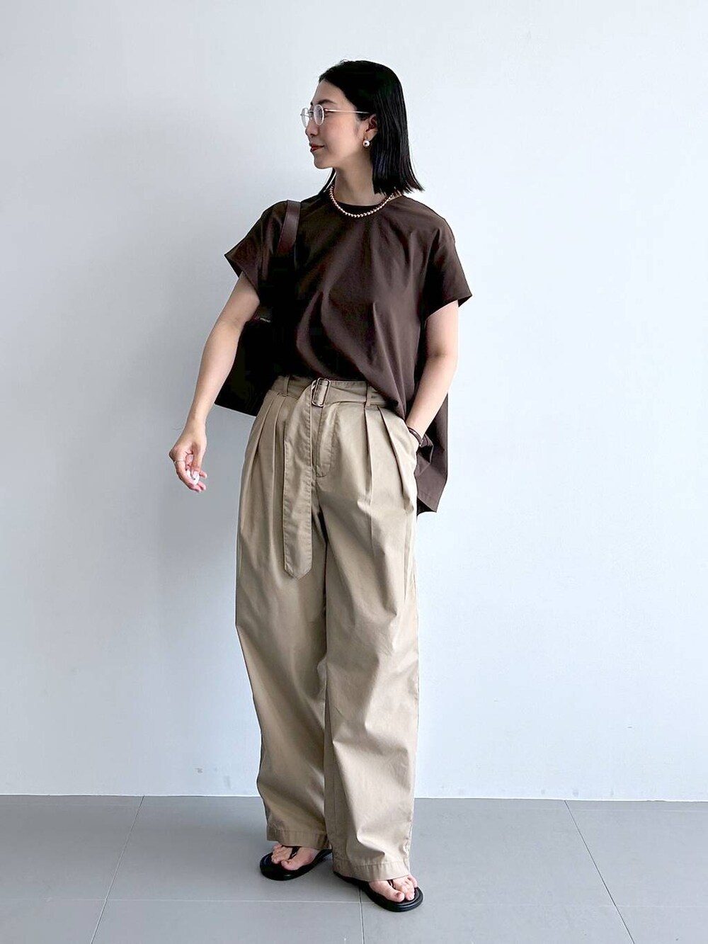 ベージュ系のチノパンツ、ブラウン系のサンダル、ブラウン系のハンドバッグを着用したレディースの夏コーディネートの4枚目の写真