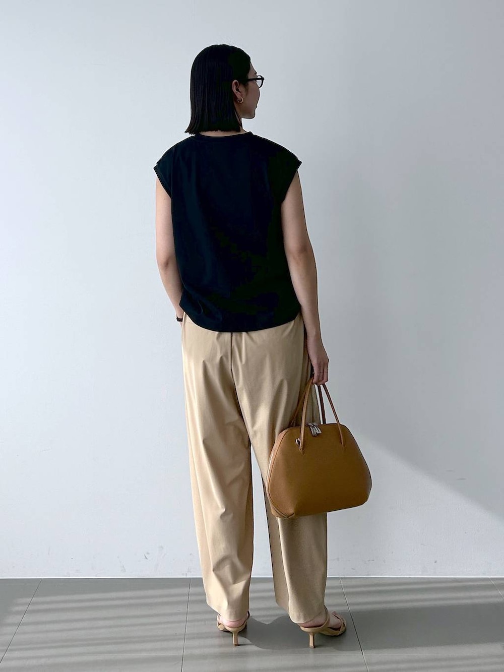 ブラック系のTシャツ/カットソー、ブラウン系のトートバッグ、ベージュ系のその他パンツを着用したレディースの春コーディネートの3枚目の写真