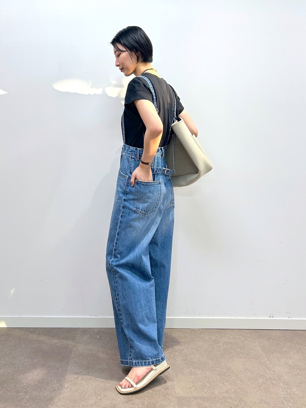 ブラック系のTシャツ/カットソー、ブルー系のデニムパンツ、ベージュ系のトートバッグを着用したレディースの春コーディネートの2枚目の写真