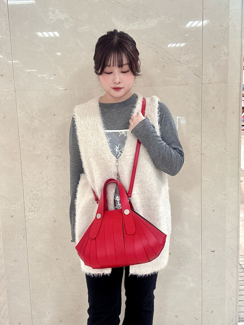 レッド系のハンドバッグを着用したレディースの冬コーディネートの2枚目の写真