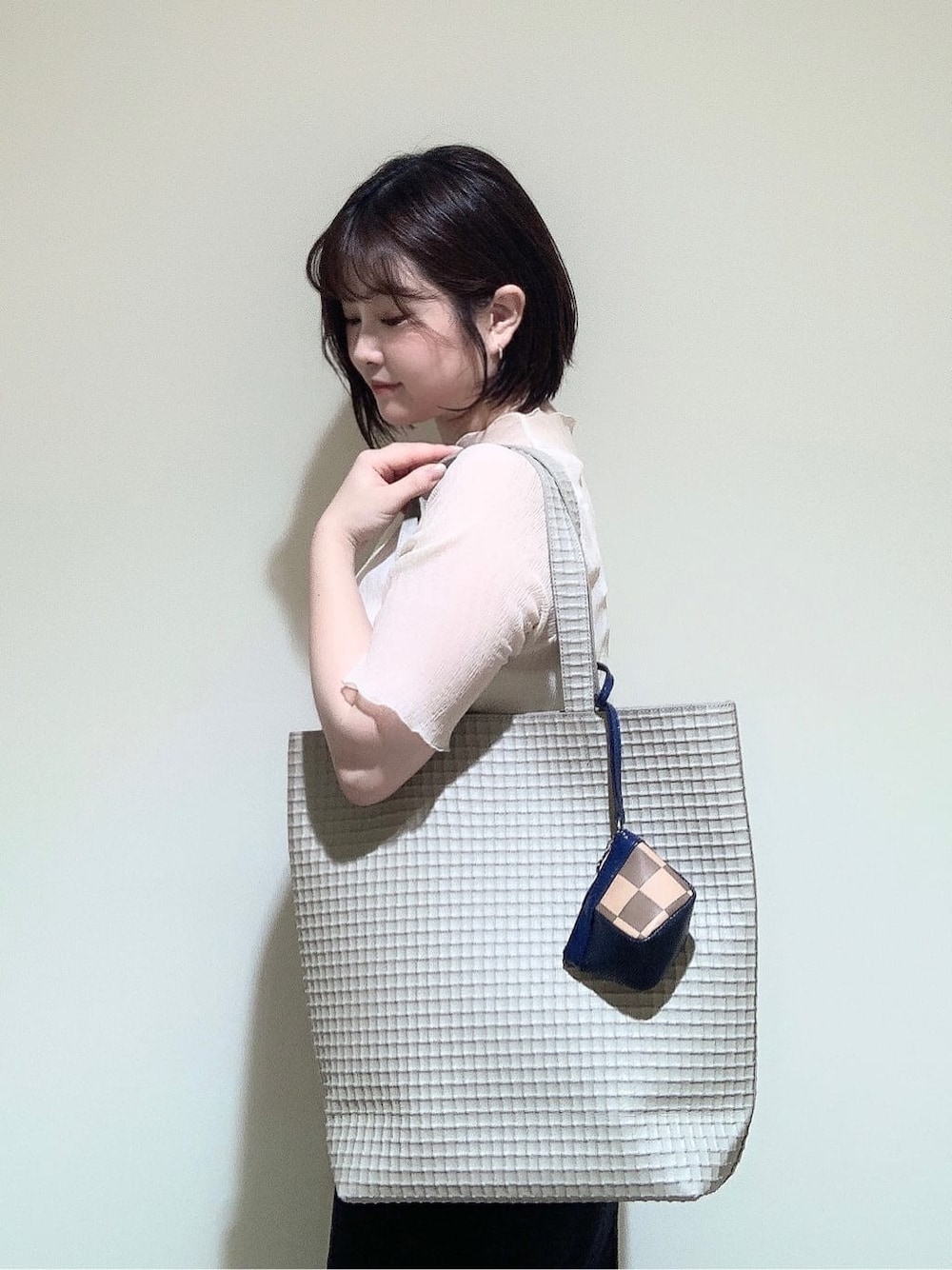 ベージュ系のトートバッグ、ベージュ系のポーチを着用したレディースの夏コーディネートの2枚目の写真