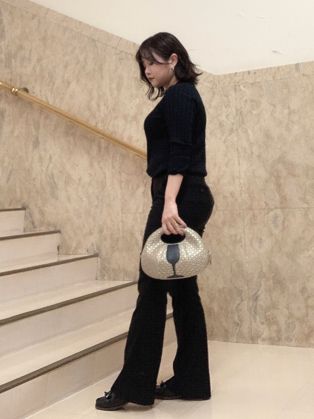 ゴールド系のハンドバッグを着用したレディースの秋コーディネートの2枚目の写真