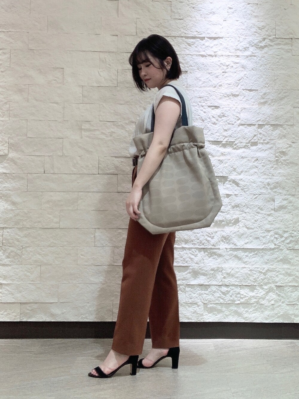 ベージュ系のトートバッグを着用したレディースの夏コーディネートの3枚目の写真