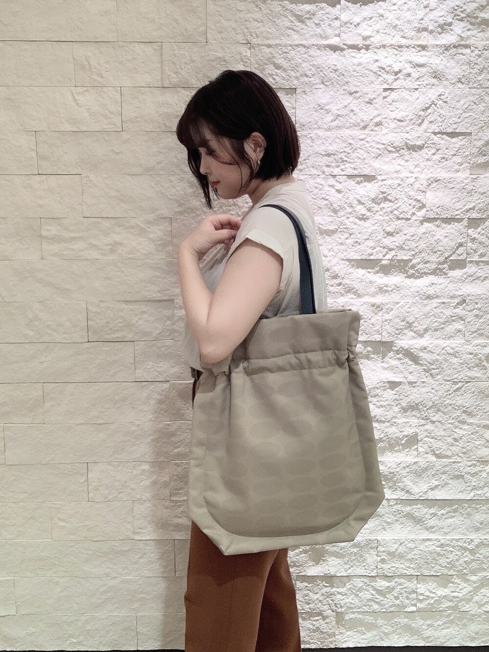 ベージュ系のトートバッグを着用したレディースの夏コーディネートの2枚目の写真