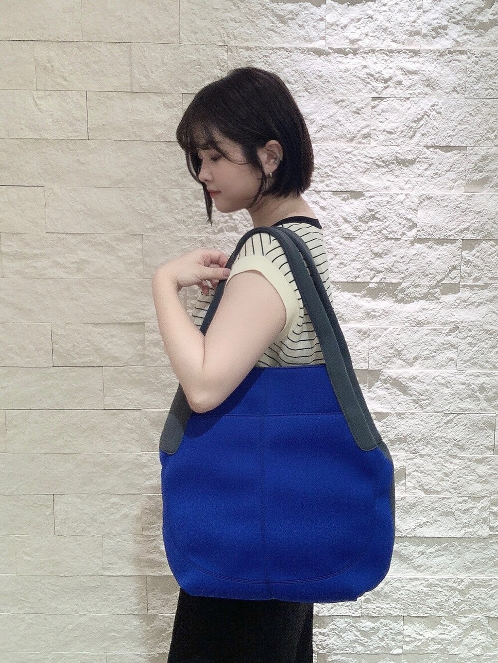 ブルー系のトートバッグを着用したレディースの夏コーディネートの2枚目の写真
