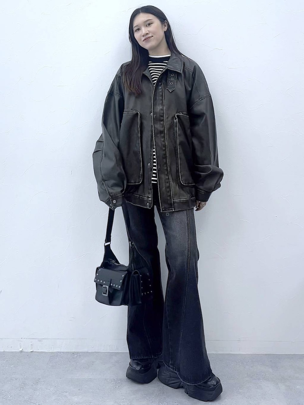 ブラック系のスニーカー、ブルー系のデニムパンツ、ブラック系のショルダーバッグを着用したレディースの秋コーディネートの7枚目の写真