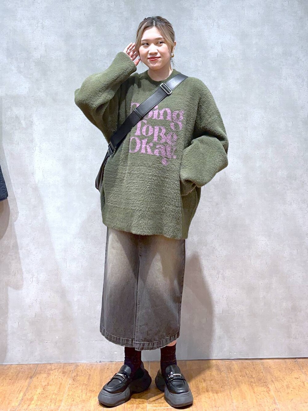 グリーン系のニット/セーター、ブラック系のショルダーバッグ、ブラック系のスカートを着用したレディースの秋コーディネートの4枚目の写真