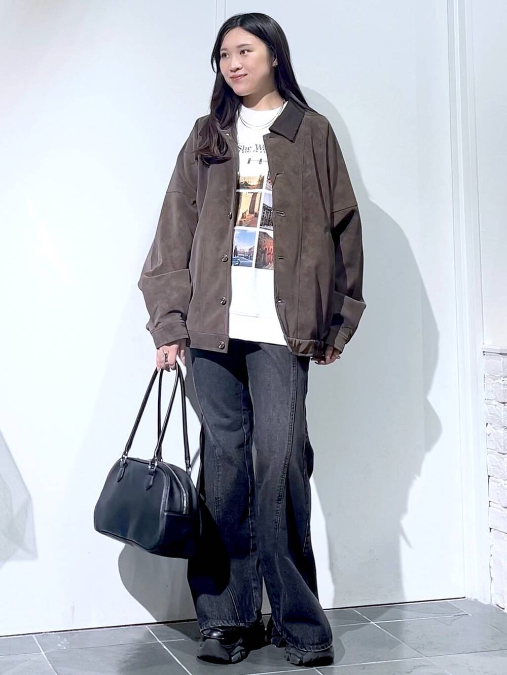 ブラック系のスニーカー、ブラック系のデニムパンツ、ブラック系のボストンバッグを着用したレディースの秋コーディネートの3枚目の写真