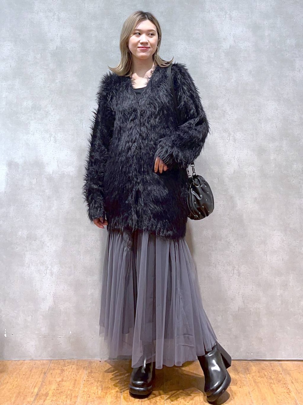 ブラック系のカーディガン/ボレロ、ブラック系のショルダーバッグ、ブラック系のブーツを着用したレディースの秋コーディネートの3枚目の写真