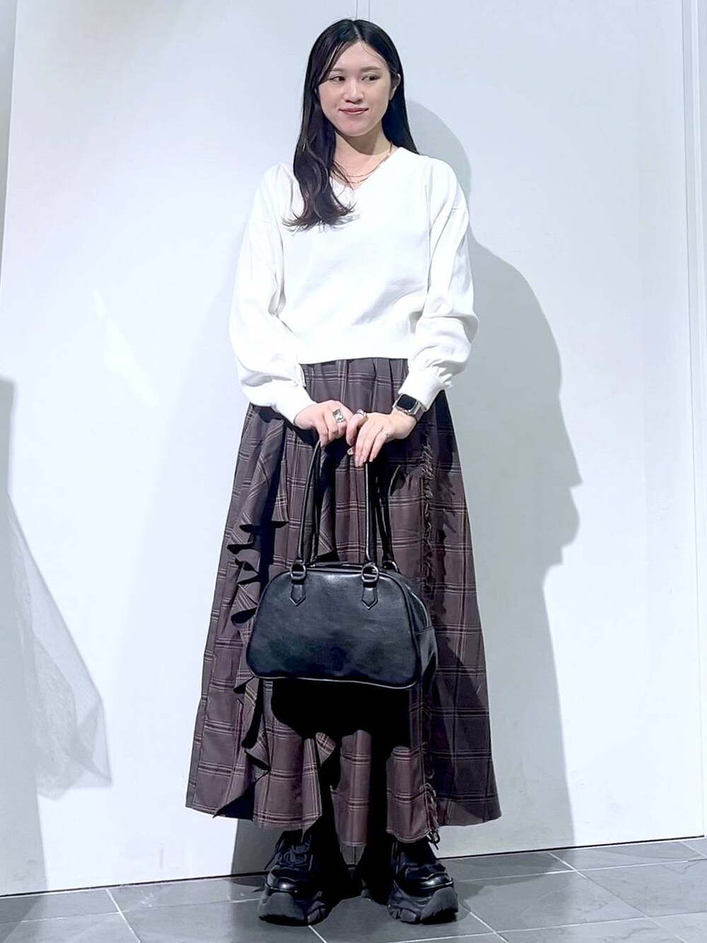 ブラック系のスニーカー、ブラック系のボストンバッグ、ホワイト系のニット/セーターを着用したレディースの秋コーディネートの2枚目の写真