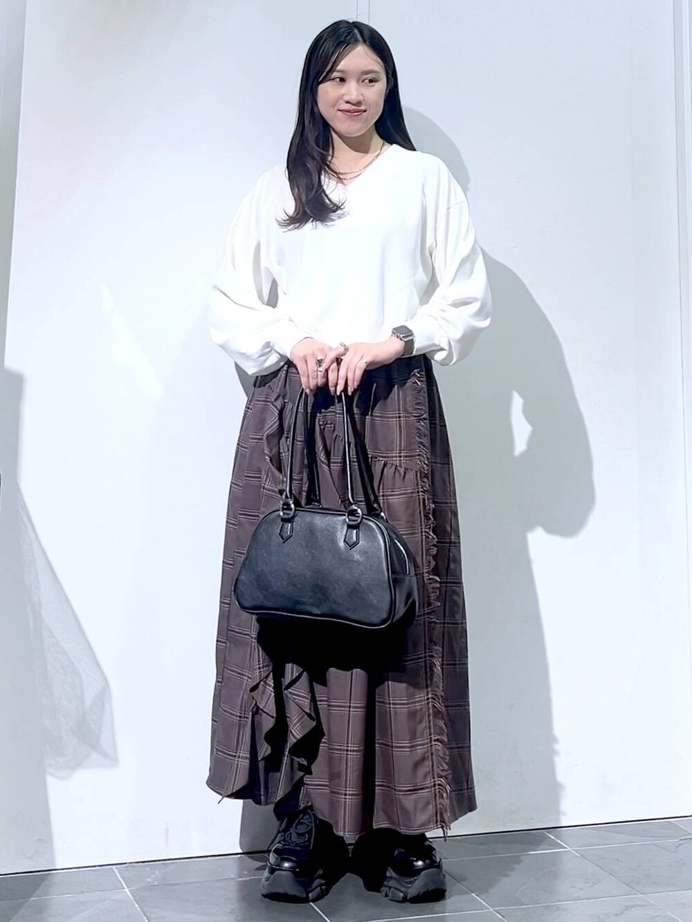 ブラック系のスニーカー、ブラック系のボストンバッグ、ホワイト系のニット/セーターを着用したレディースの秋コーディネートの6枚目の写真