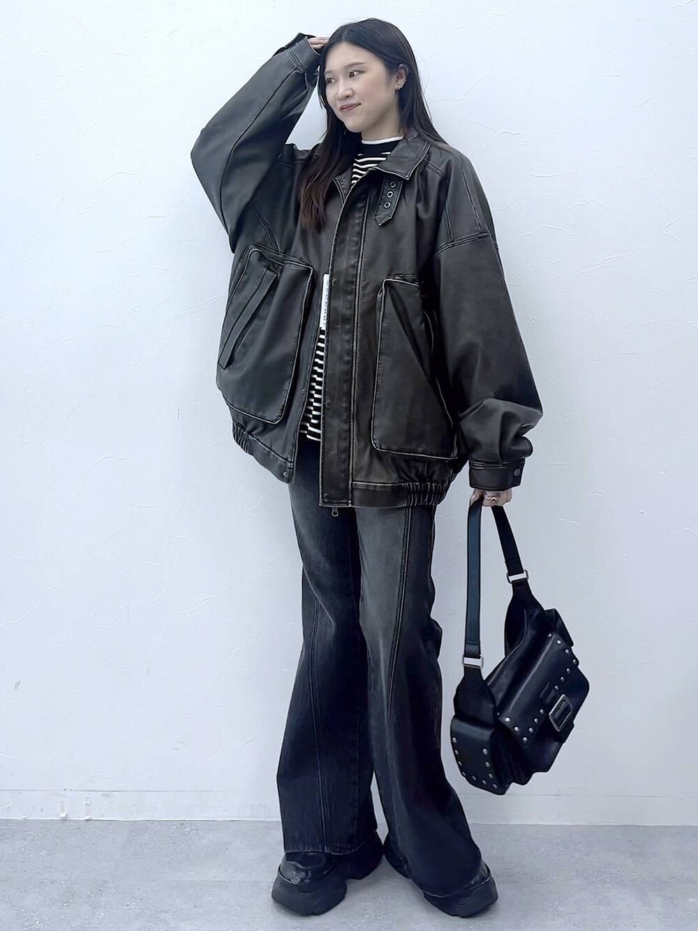 ブラック系のスニーカー、ブルー系のデニムパンツ、ブラック系のショルダーバッグを着用したレディースの秋コーディネートの5枚目の写真