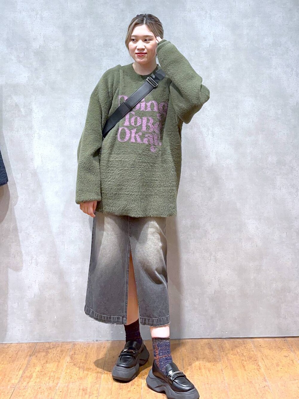 グリーン系のニット/セーター、ブラック系のショルダーバッグ、ブラック系のスカートを着用したレディースの秋コーディネートの3枚目の写真