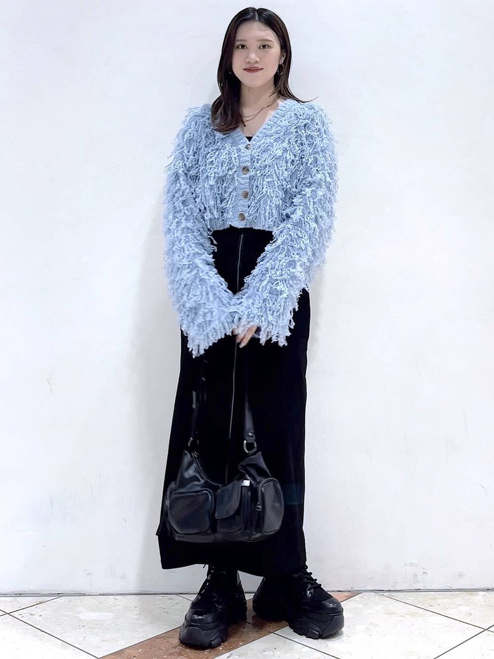 ブラック系のブーツ、ブラック系のショルダーバッグ、ブラック系のスカートを着用したレディースの秋コーディネートの8枚目の写真