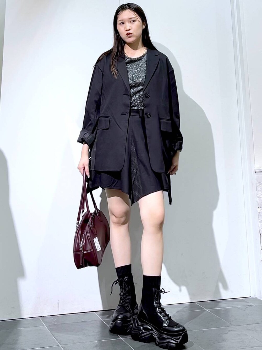 ブラック系のブーツ、シルバー系のTシャツ/カットソー、ブラック系のスカートを着用したレディースの秋コーディネートの5枚目の写真