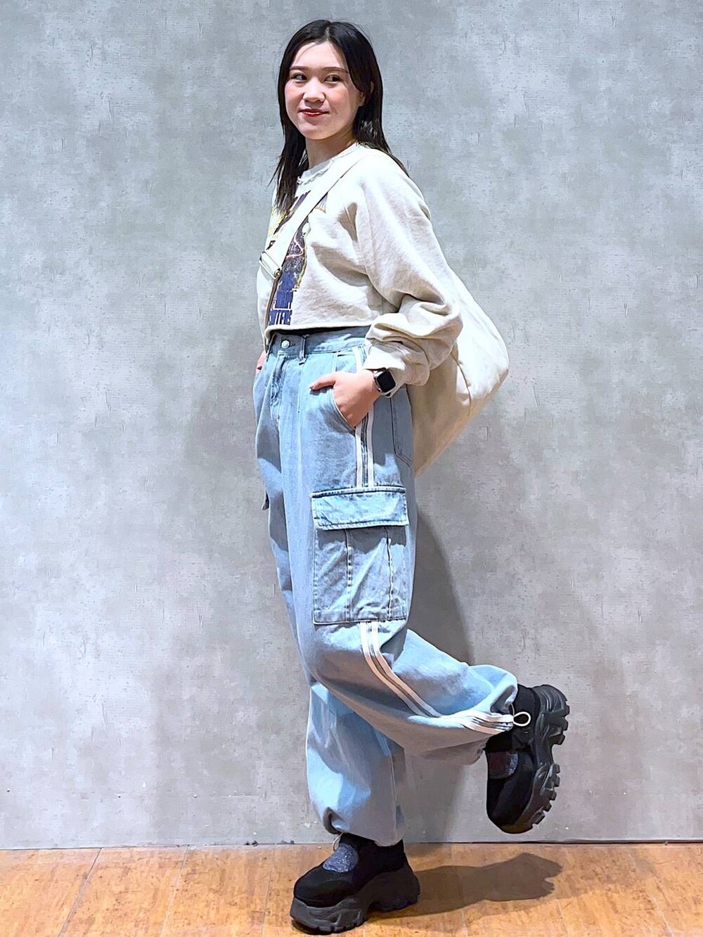 ベージュ系のスウェット、ホワイト系のショルダーバッグ、ブラック系のスニーカーを着用したレディースの春コーディネートの3枚目の写真