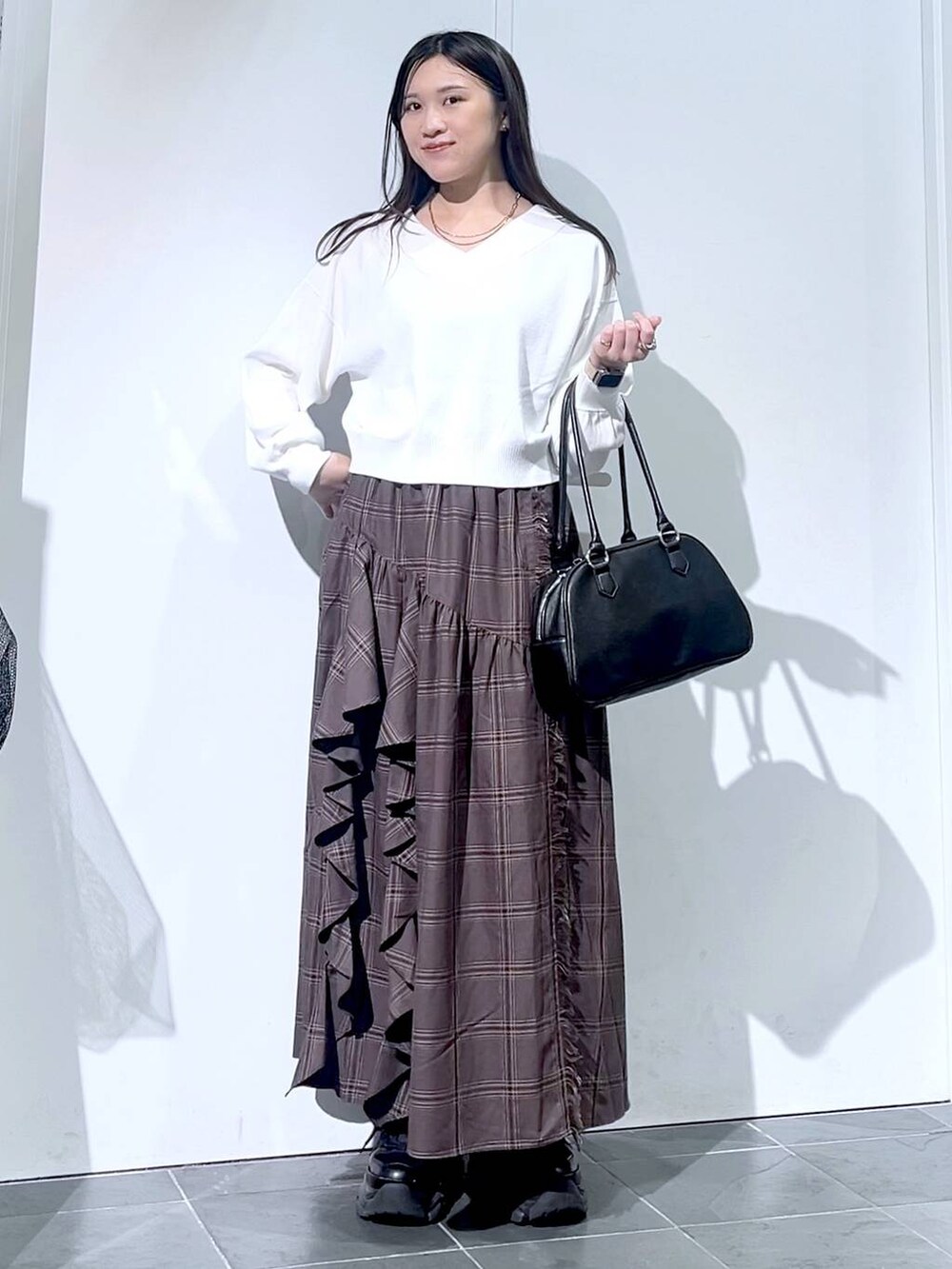 ブラック系のスニーカー、ブラック系のボストンバッグ、ホワイト系のニット/セーターを着用したレディースの秋コーディネートの7枚目の写真