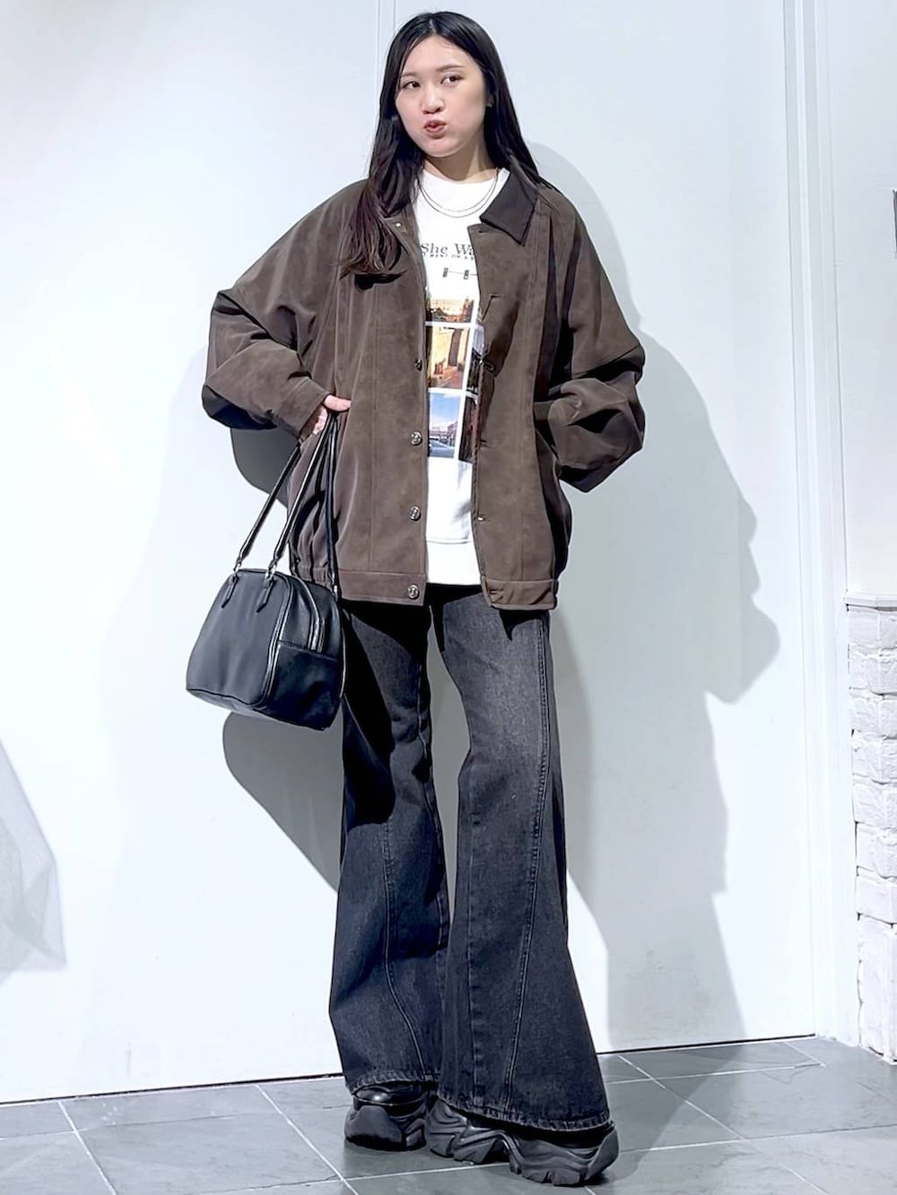 ブラック系のスニーカー、ブラック系のデニムパンツ、ブラック系のボストンバッグを着用したレディースの秋コーディネートの7枚目の写真