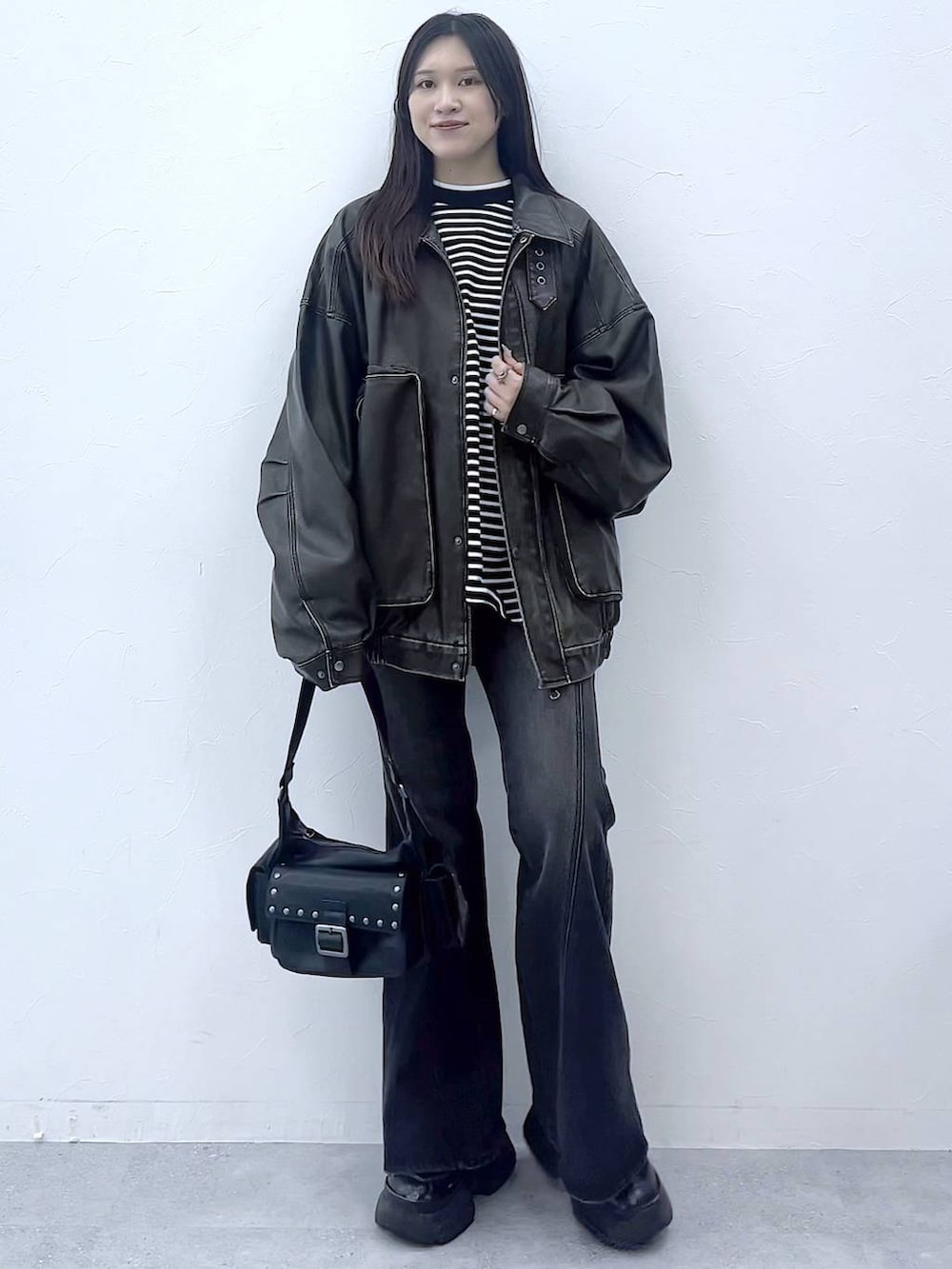 ブラック系のスニーカー、ブルー系のデニムパンツ、ブラック系のショルダーバッグを着用したレディースの秋コーディネートの2枚目の写真