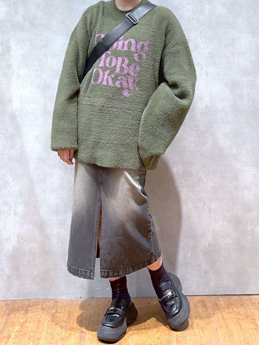 グリーン系のニット/セーター、ブラック系のショルダーバッグ、ブラック系のスカートを着用したレディースの秋コーディネートの5枚目の写真