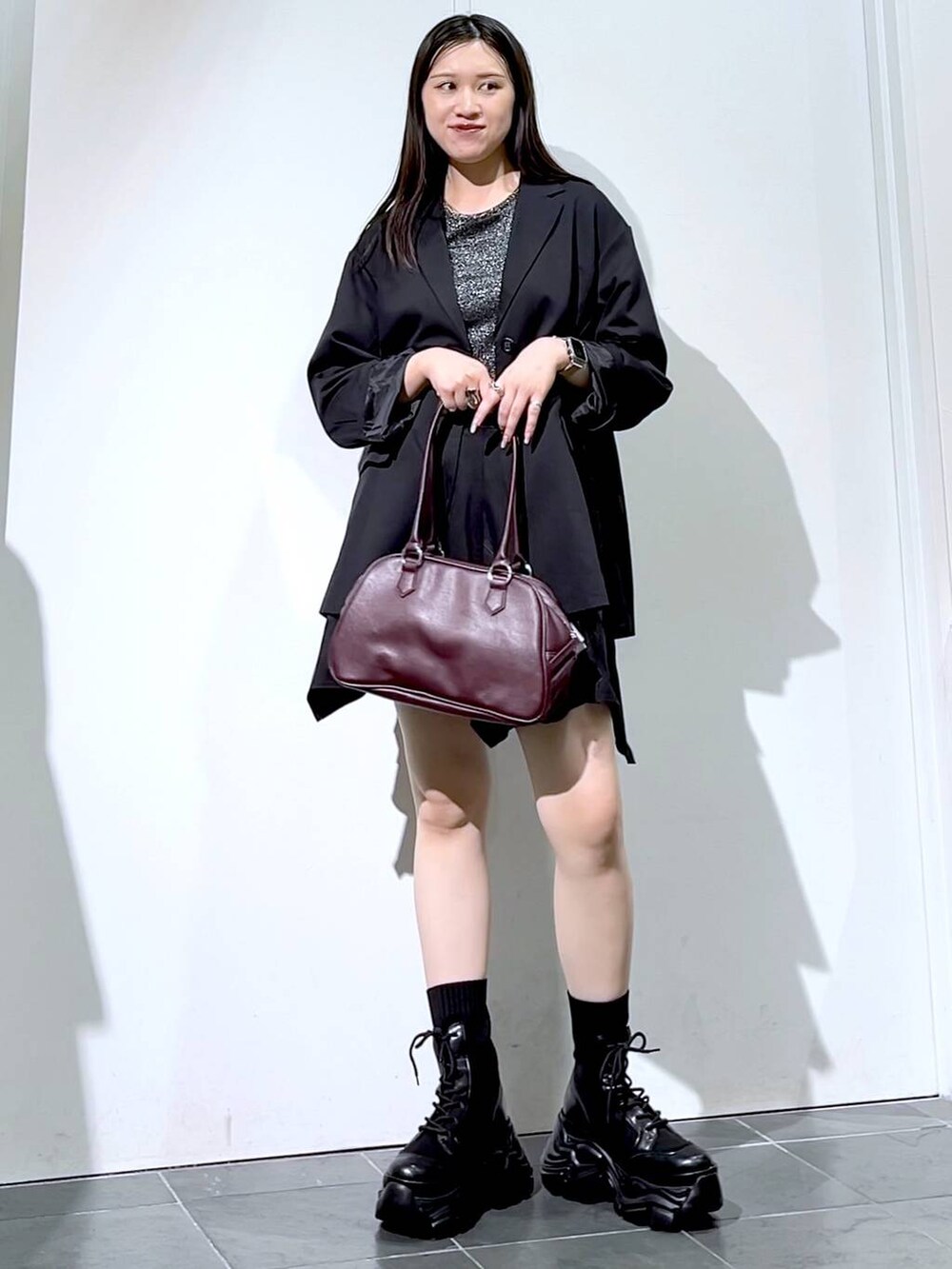 ブラック系のブーツ、シルバー系のTシャツ/カットソー、ブラック系のスカートを着用したレディースの秋コーディネートの2枚目の写真