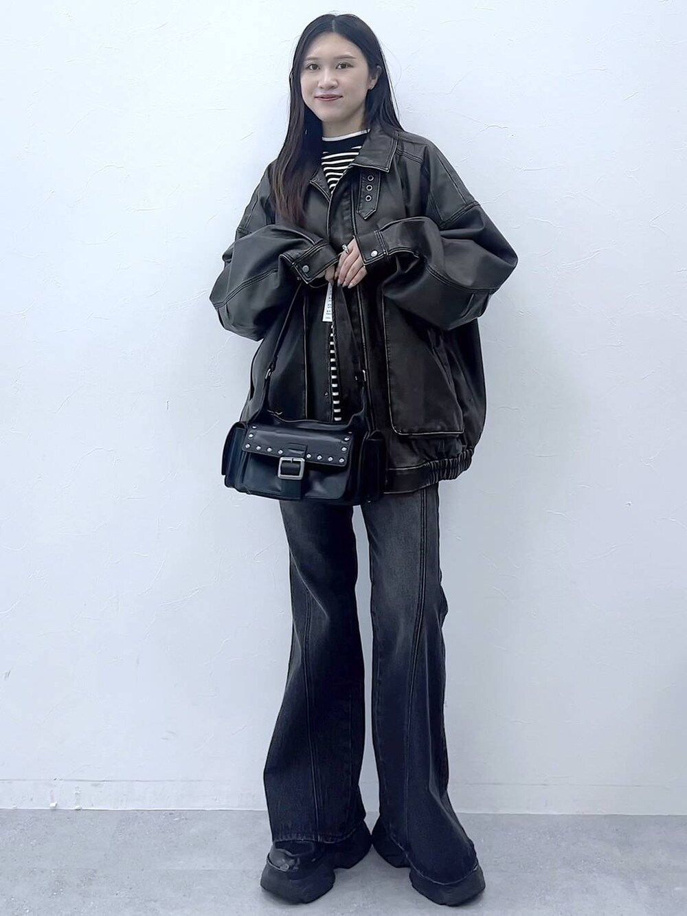 ブラック系のスニーカー、ブルー系のデニムパンツ、ブラック系のショルダーバッグを着用したレディースの秋コーディネートの6枚目の写真