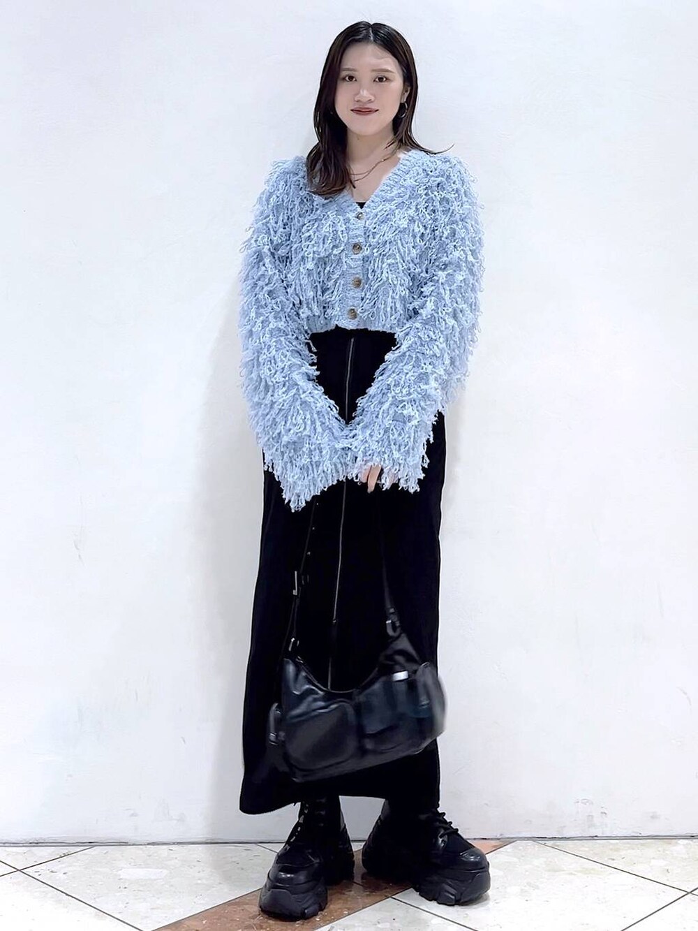 ブラック系のブーツ、ブラック系のショルダーバッグ、ブラック系のスカートを着用したレディースの秋コーディネートの3枚目の写真