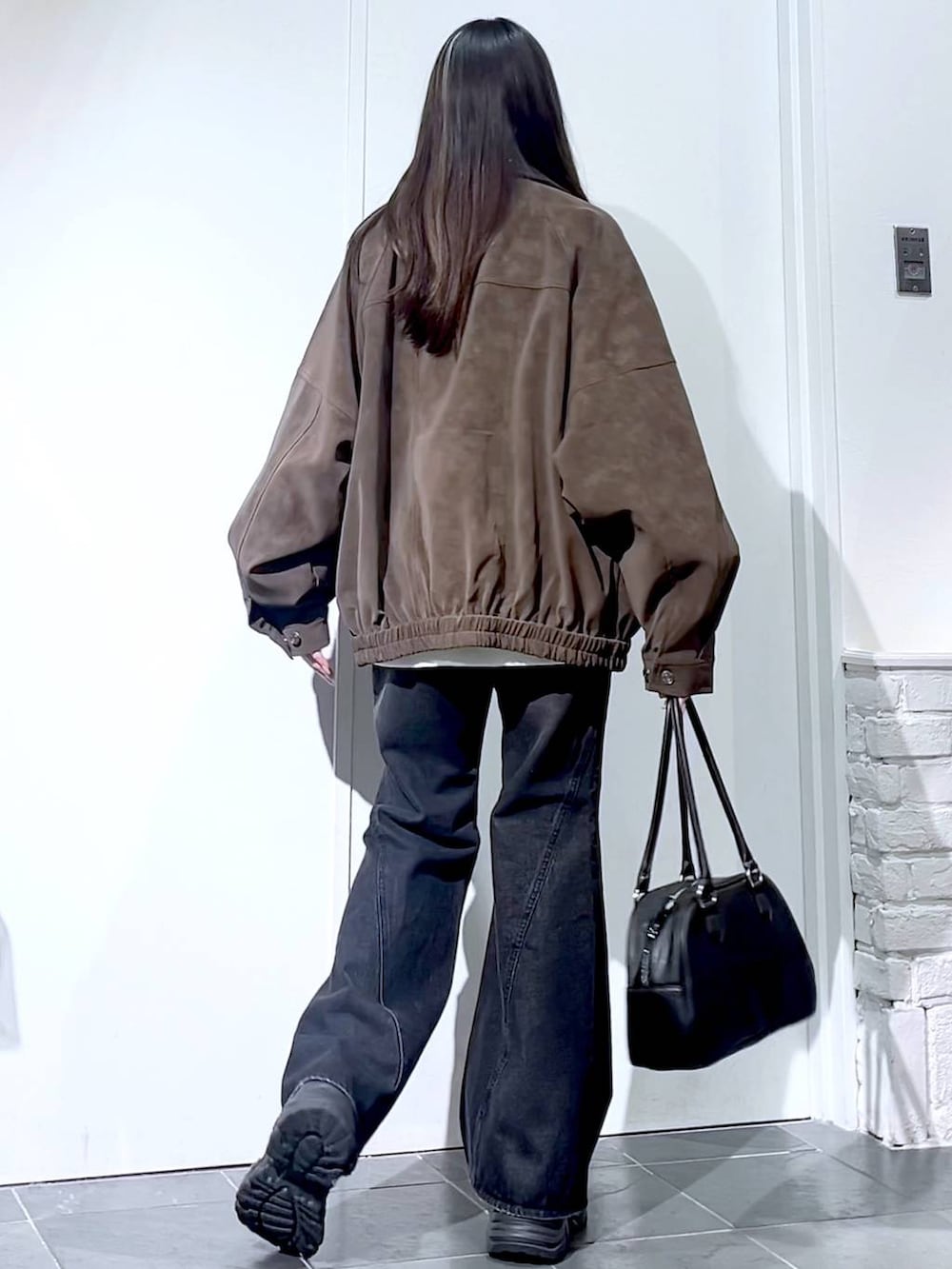 ブラック系のスニーカー、ブラック系のデニムパンツ、ブラック系のボストンバッグを着用したレディースの秋コーディネートの9枚目の写真