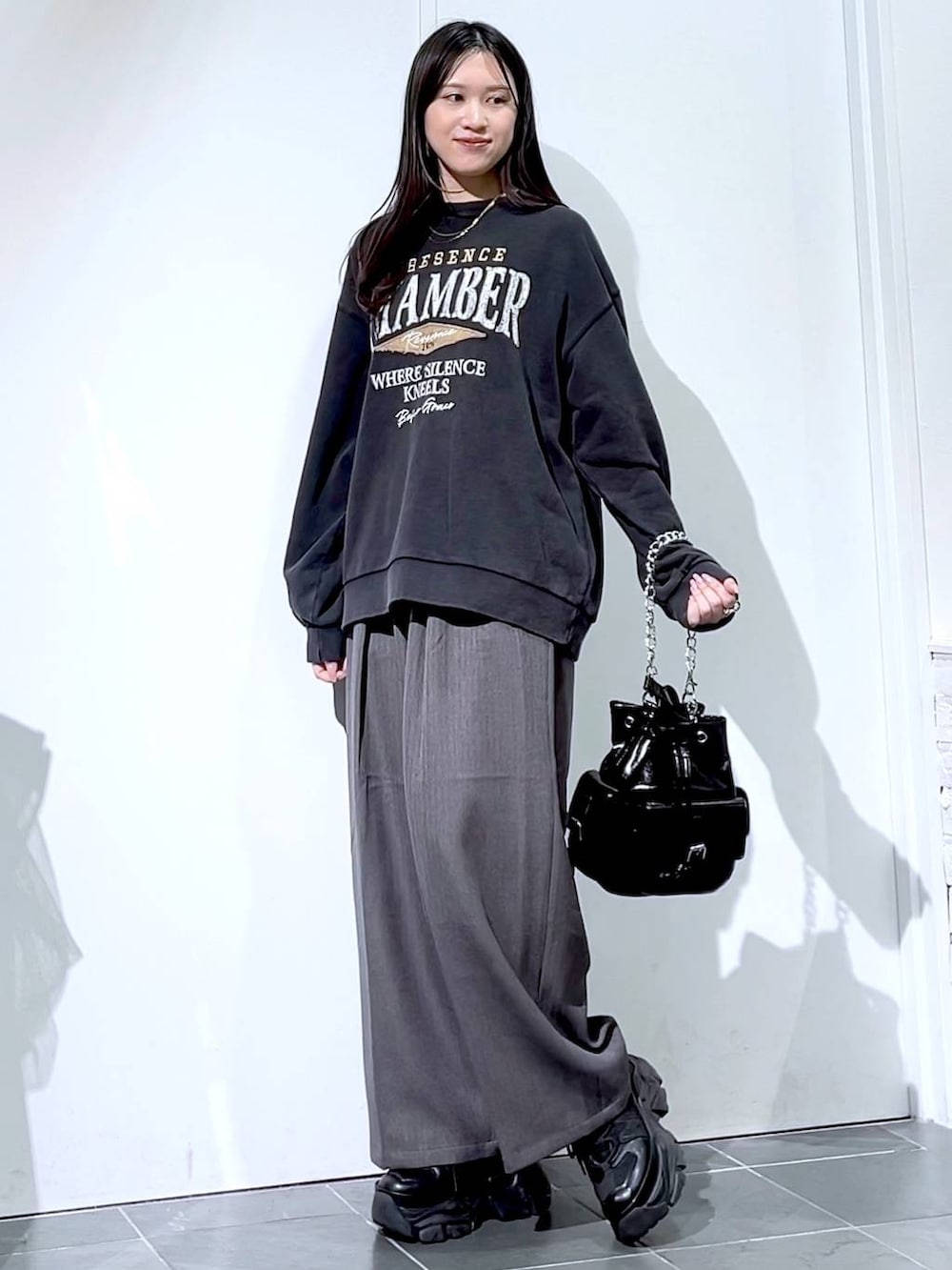 ブラック系のスニーカー、グレー系のスウェット、ブラック系のショルダーバッグを着用したレディースの秋コーディネートの2枚目の写真