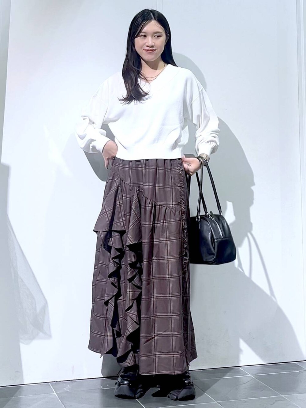 ブラック系のスニーカー、ブラック系のボストンバッグ、ホワイト系のニット/セーターを着用したレディースの秋コーディネートの5枚目の写真