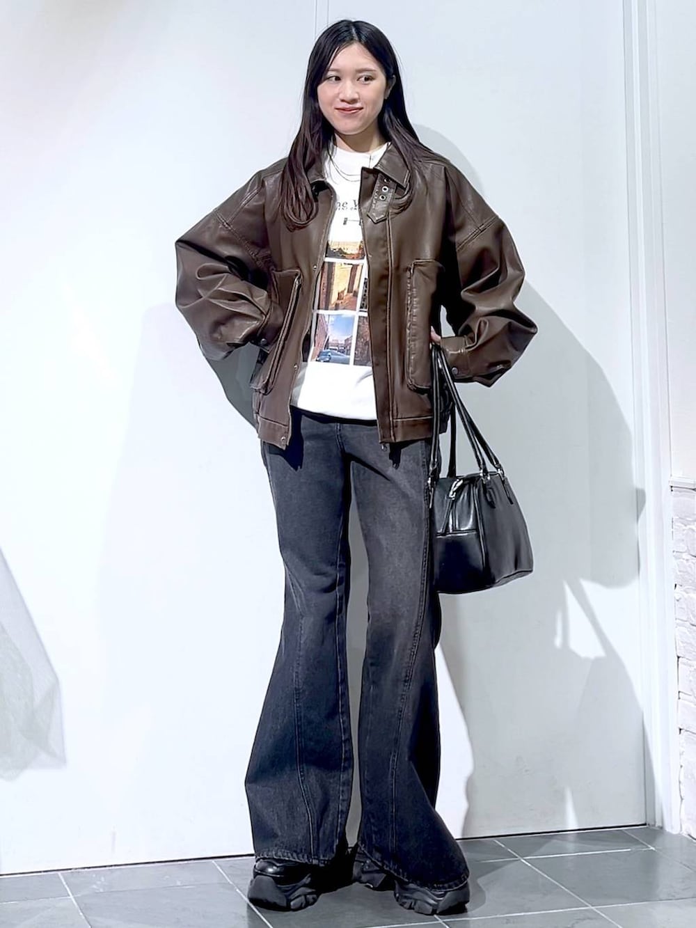 ブラック系のスニーカー、ブラック系のデニムパンツ、ブラック系のボストンバッグを着用したレディースの秋コーディネートの6枚目の写真