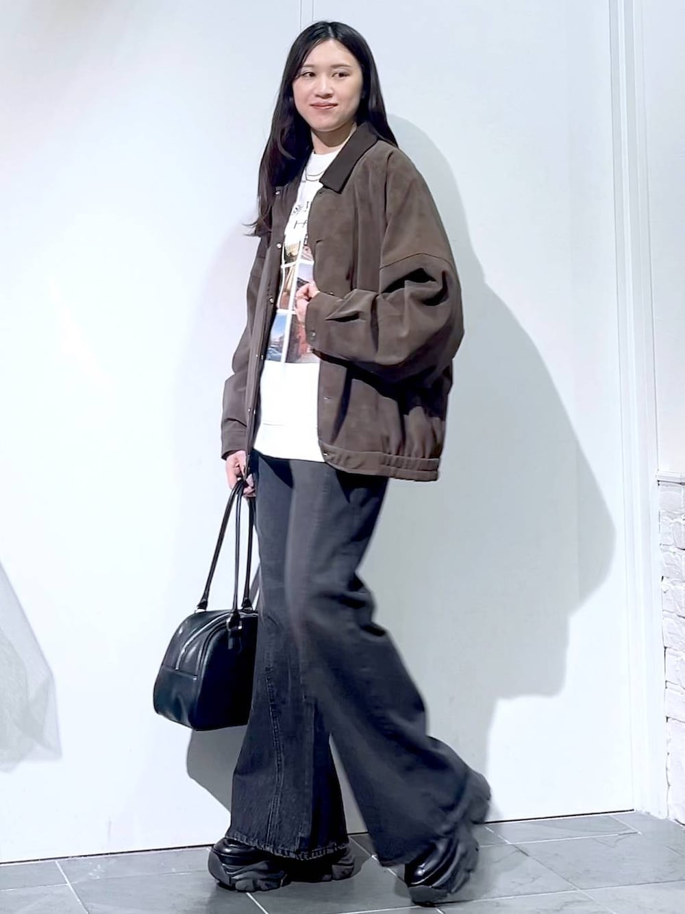 ブラック系のスニーカー、ブラック系のデニムパンツ、ブラック系のボストンバッグを着用したレディースの秋コーディネートの5枚目の写真