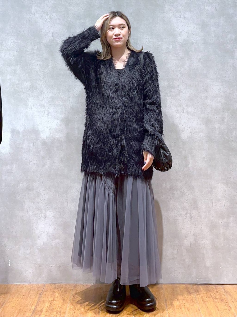 ブラック系のカーディガン/ボレロ、ブラック系のショルダーバッグ、ブラック系のブーツを着用したレディースの秋コーディネートの2枚目の写真