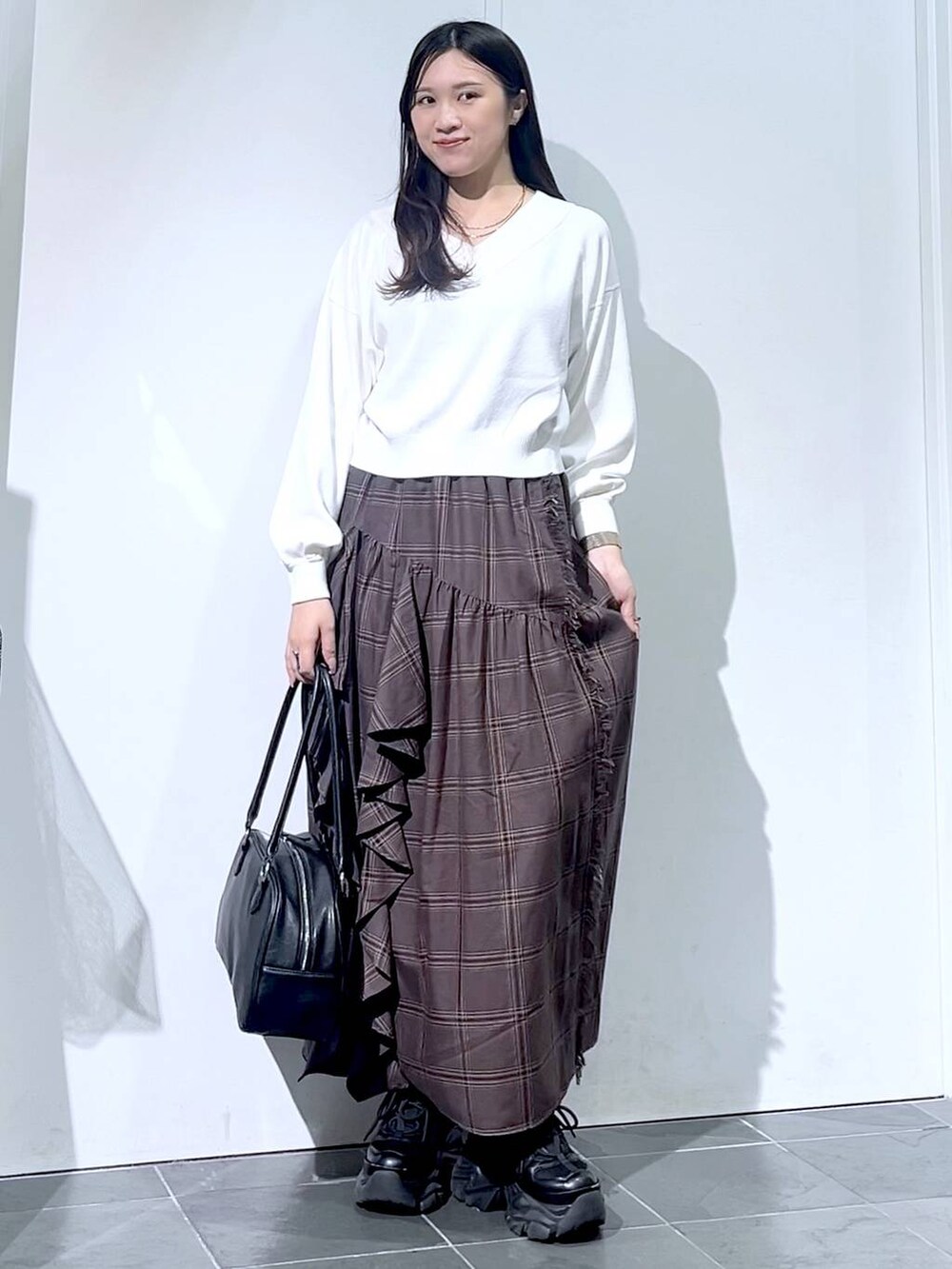 ブラック系のスニーカー、ブラック系のボストンバッグ、ホワイト系のニット/セーターを着用したレディースの秋コーディネートの4枚目の写真