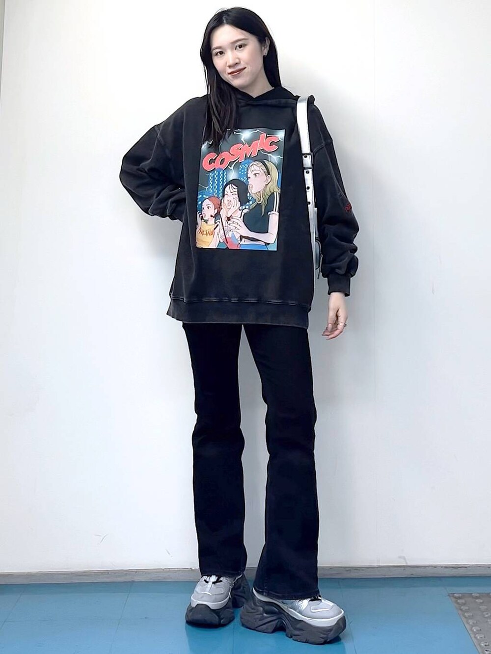 シルバー系のショルダーバッグ、ブラック系のデニムパンツ、ブラック系のパーカーを着用したレディースの冬コーディネートの3枚目の写真