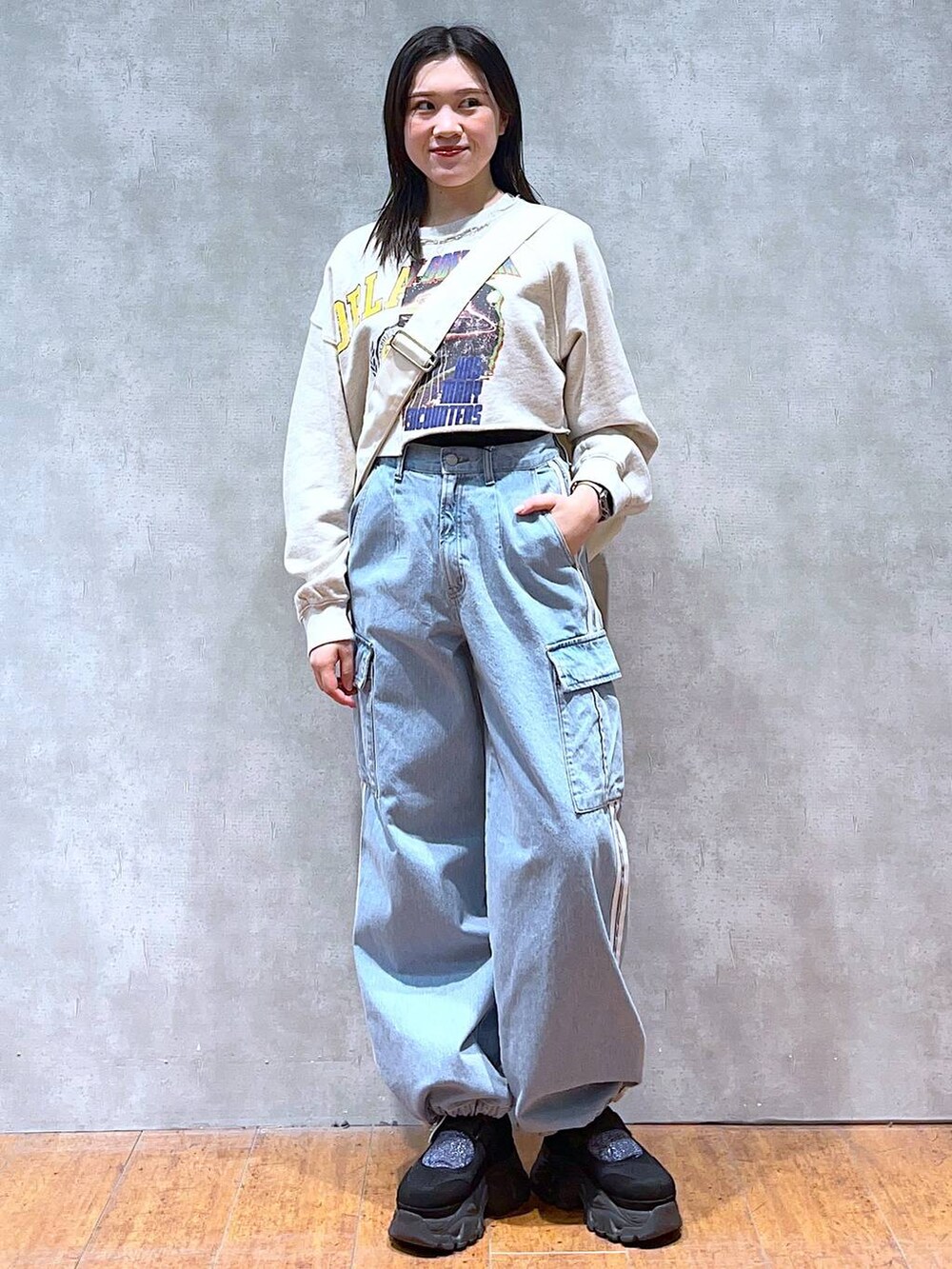 ベージュ系のスウェット、ホワイト系のショルダーバッグ、ブラック系のスニーカーを着用したレディースの春コーディネートの2枚目の写真