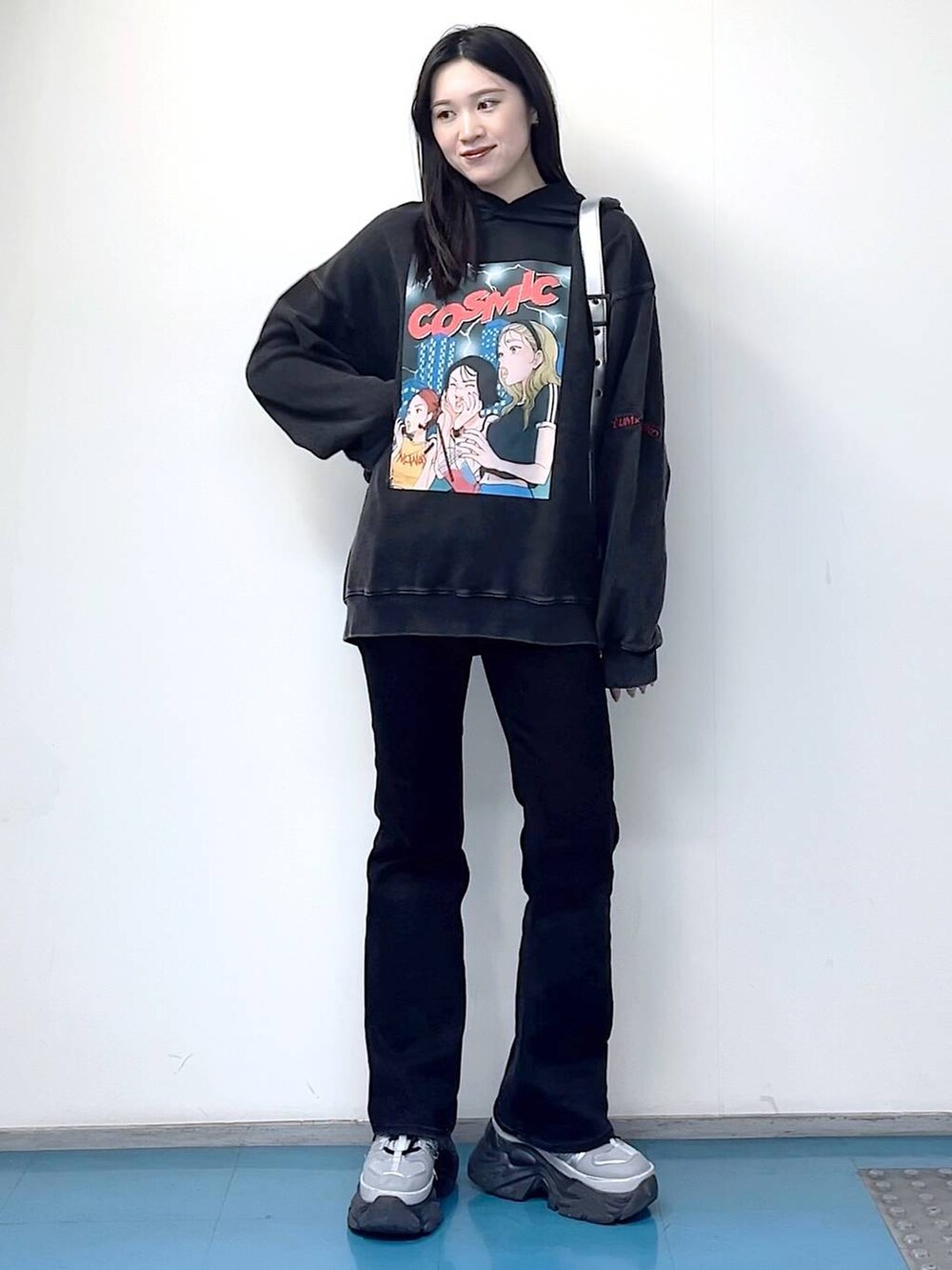 シルバー系のショルダーバッグ、ブラック系のデニムパンツ、ブラック系のパーカーを着用したレディースの冬コーディネートの2枚目の写真