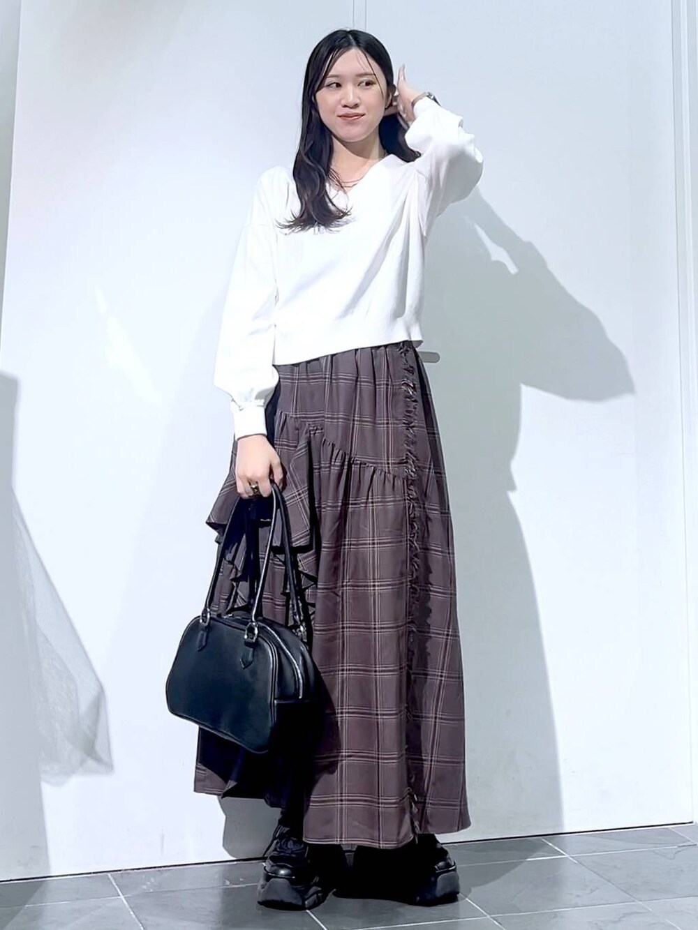 ブラック系のスニーカー、ブラック系のボストンバッグ、ホワイト系のニット/セーターを着用したレディースの秋コーディネートの3枚目の写真