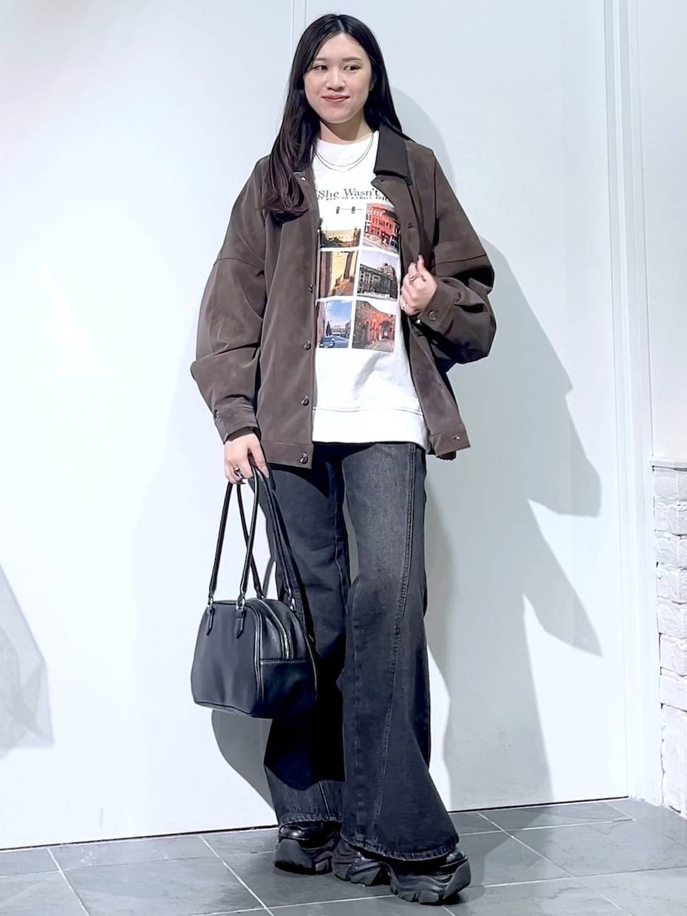 ブラック系のスニーカー、ブラック系のデニムパンツ、ブラック系のボストンバッグを着用したレディースの秋コーディネートの4枚目の写真