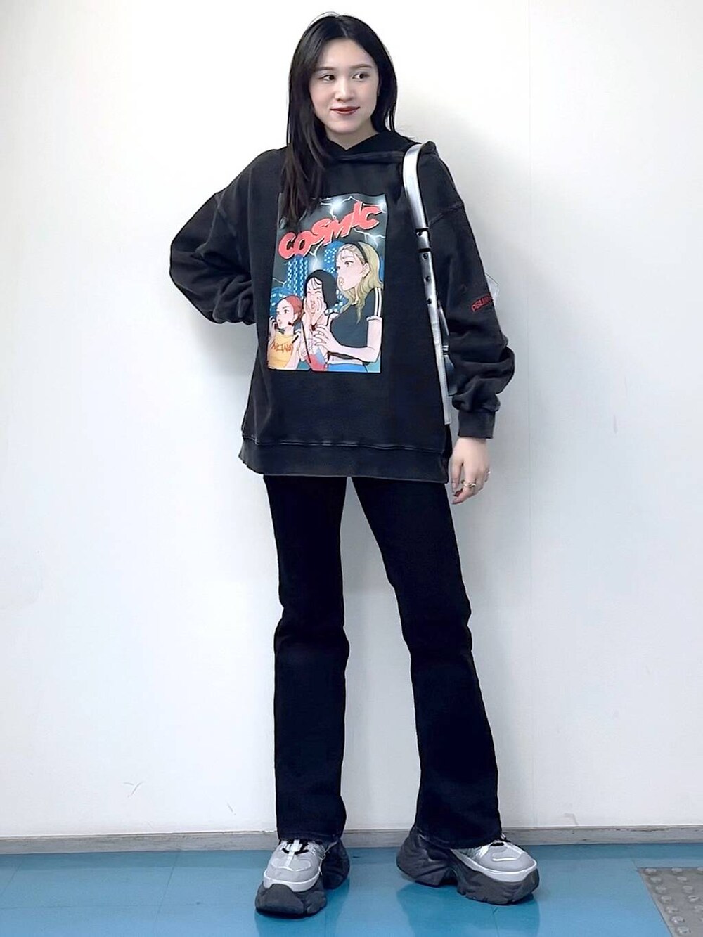 シルバー系のショルダーバッグ、ブラック系のデニムパンツ、ブラック系のパーカーを着用したレディースの冬コーディネートの5枚目の写真