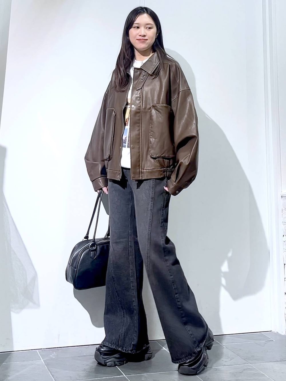 ブラック系のスニーカー、ブラック系のデニムパンツ、ブラック系のボストンバッグを着用したレディースの秋コーディネートの3枚目の写真