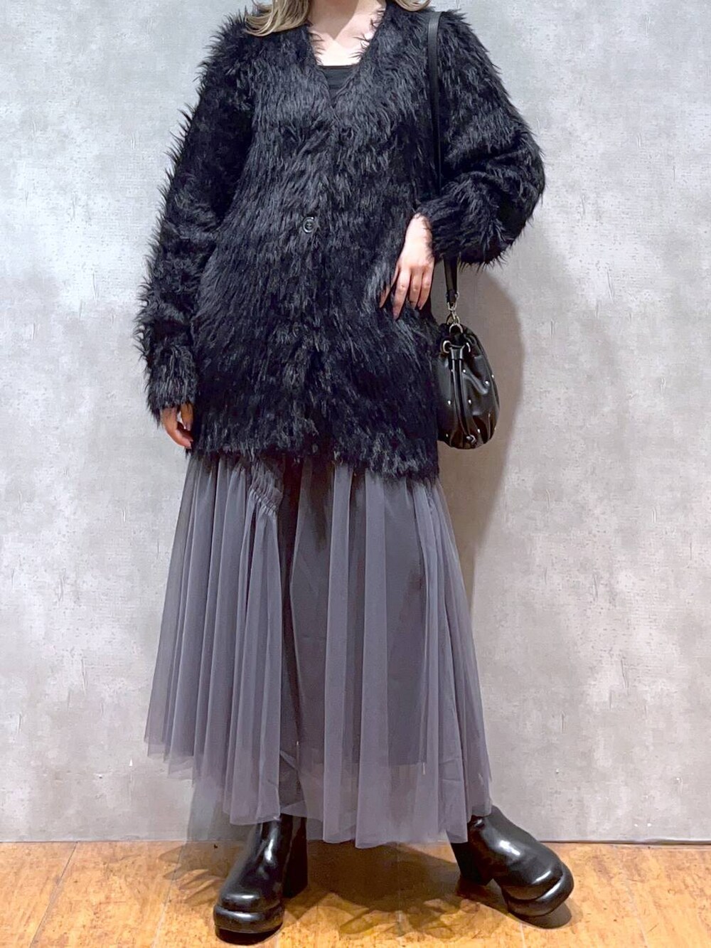 ブラック系のカーディガン/ボレロ、ブラック系のショルダーバッグ、ブラック系のブーツを着用したレディースの秋コーディネートの5枚目の写真