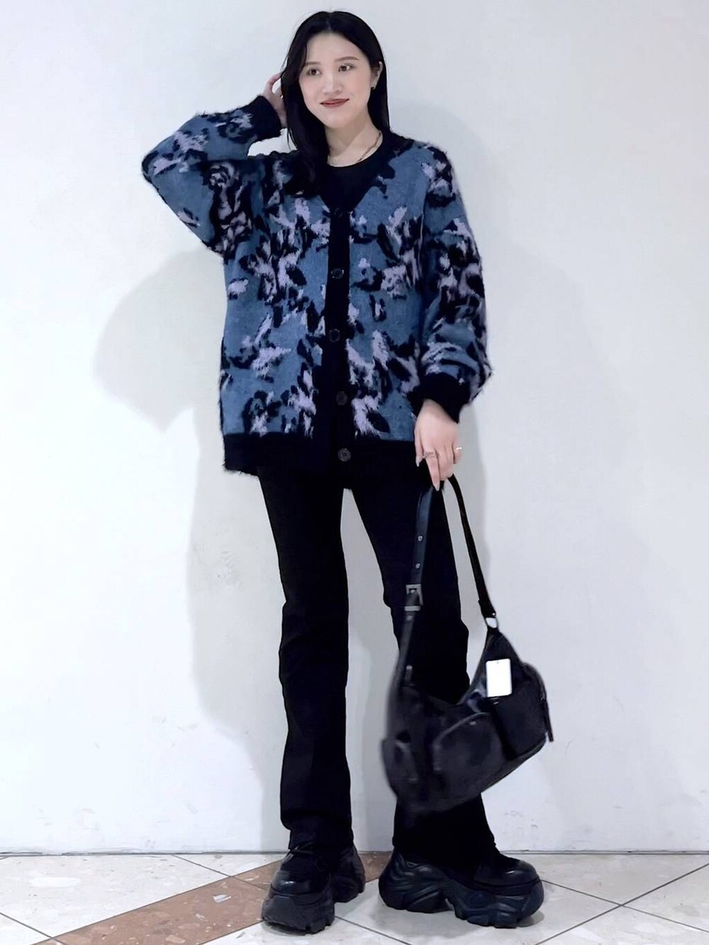 ブラック系のブーツ、ブラック系のショルダーバッグ、ブルー系のニット/セーターを着用したレディースの冬コーディネートの2枚目の写真