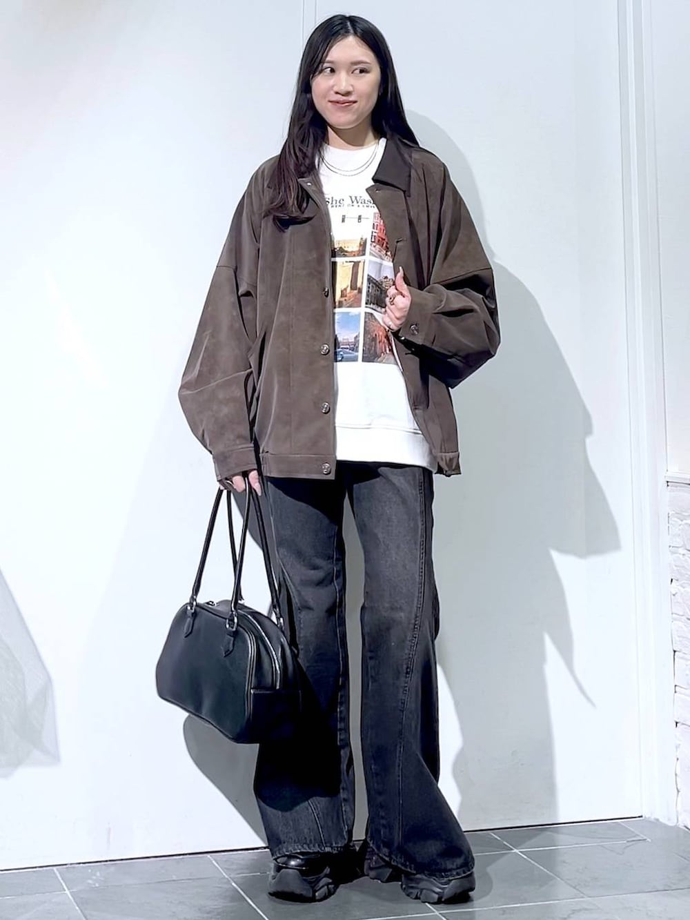 ブラック系のスニーカー、ブラック系のデニムパンツ、ブラック系のボストンバッグを着用したレディースの秋コーディネートの6枚目の写真