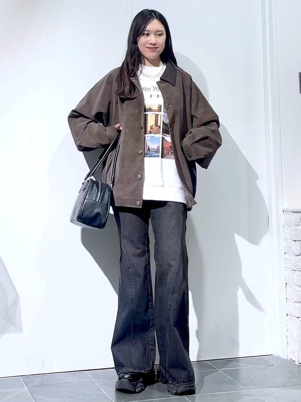 ブラック系のスニーカー、ブラック系のデニムパンツ、ブラック系のボストンバッグを着用したレディースの秋コーディネートの2枚目の写真