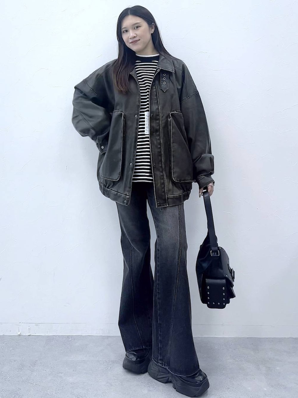 ブラック系のスニーカー、ブルー系のデニムパンツ、ブラック系のショルダーバッグを着用したレディースの秋コーディネートの3枚目の写真