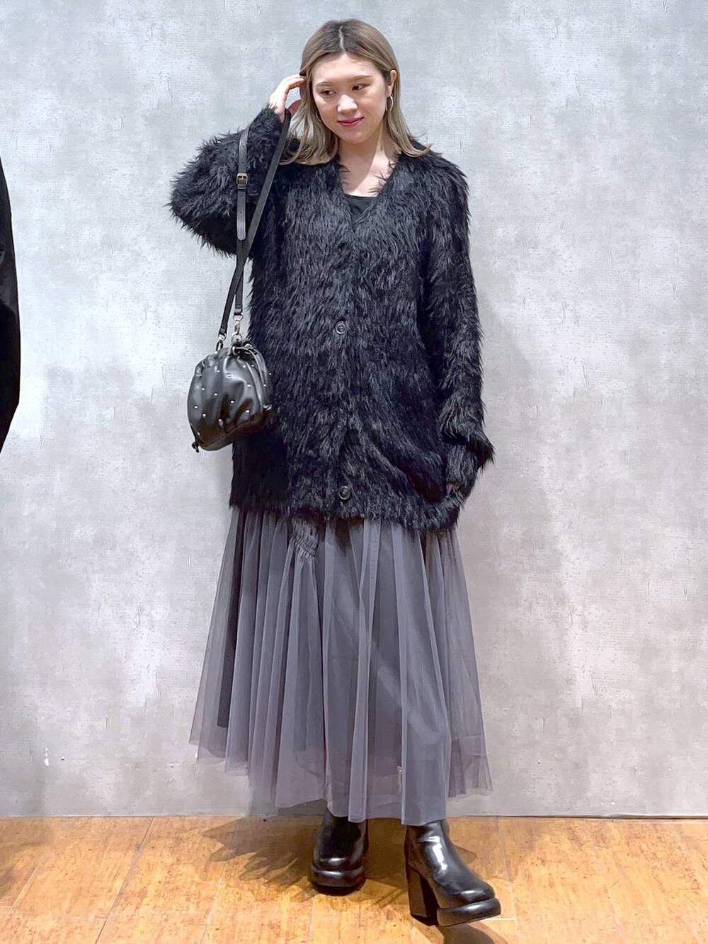 ブラック系のカーディガン/ボレロ、ブラック系のショルダーバッグ、ブラック系のブーツを着用したレディースの秋コーディネートの6枚目の写真