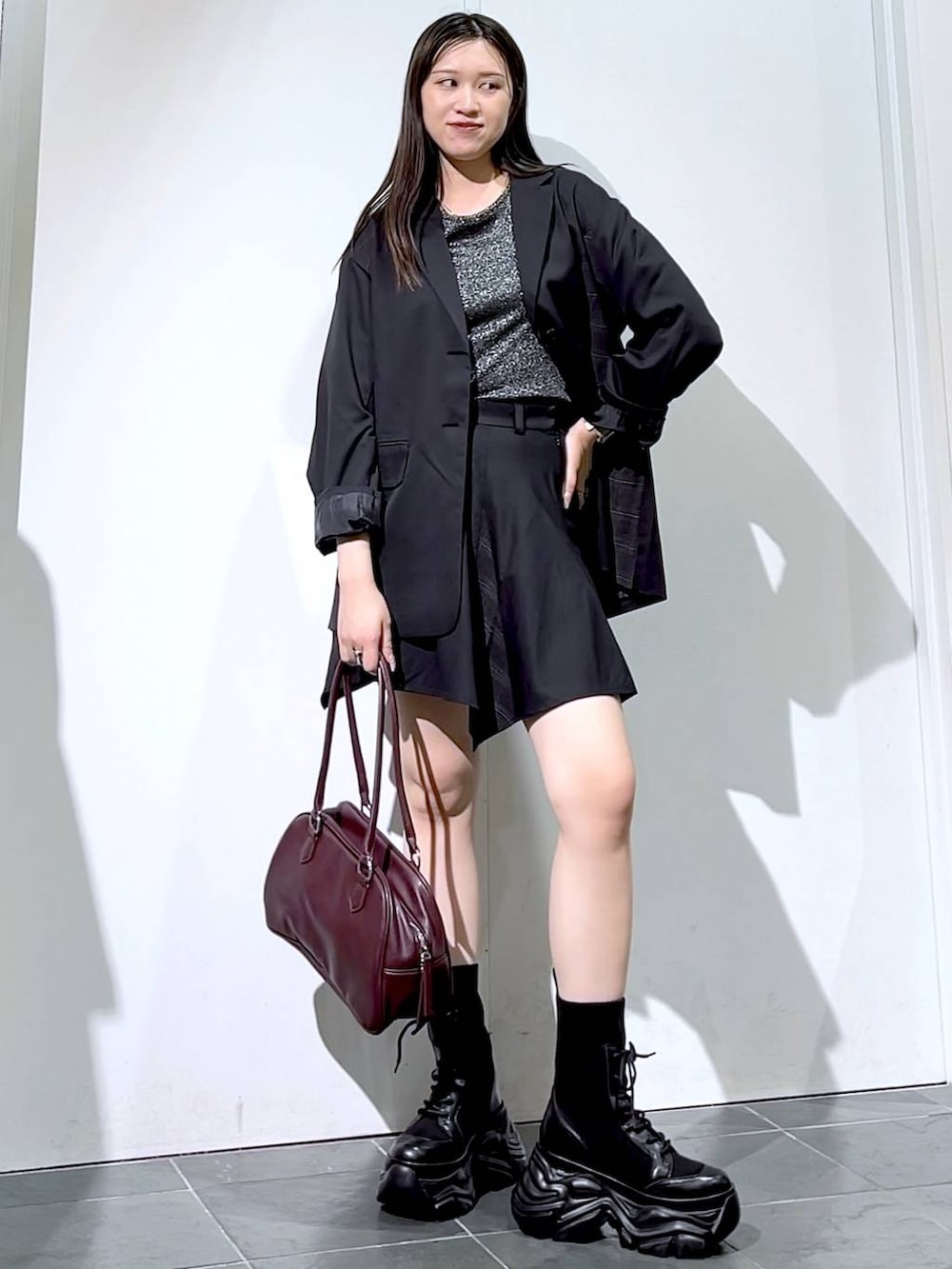 ブラック系のブーツ、シルバー系のTシャツ/カットソー、ブラック系のスカートを着用したレディースの秋コーディネートの4枚目の写真