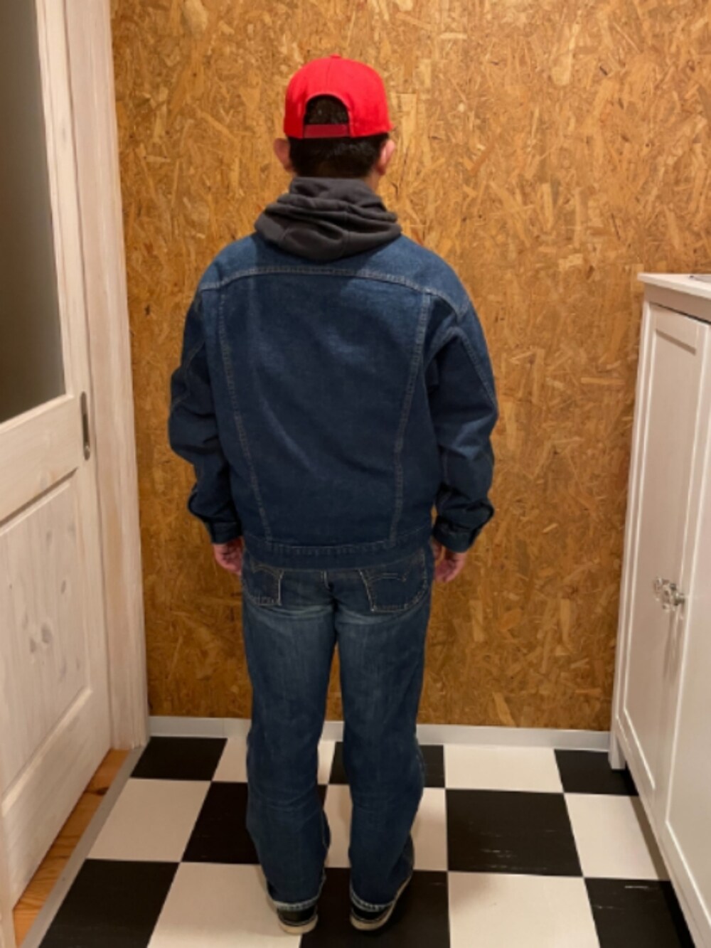 ブラック系のパーカー、ブルー系のデニムジャケット、ブルー系のデニムパンツを着用したメンズの冬コーディネートの2枚目の写真