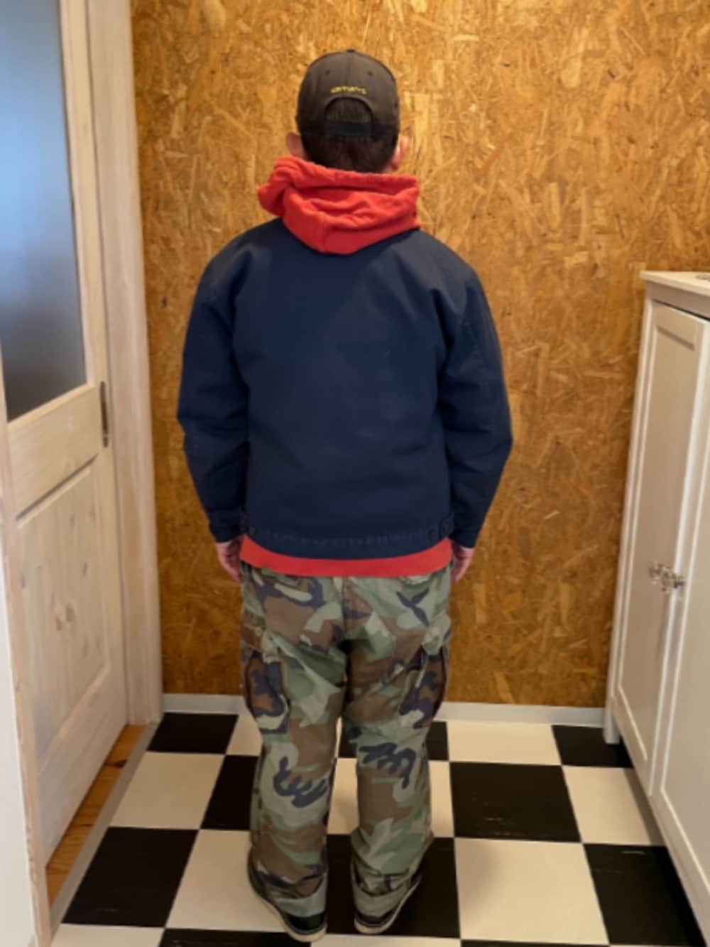 ブルー系のジャケット/アウター、オレンジ系のパーカー、グリーン系のカーゴパンツを着用したメンズの秋コーディネートの2枚目の写真